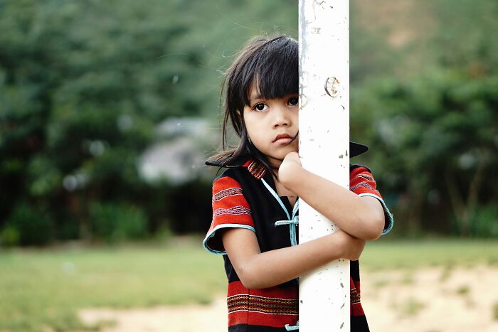 A young child in traditional clothing, looking at the camera, potentially representing culture shock for travelers.
