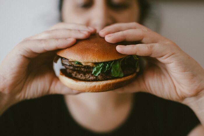 Travelers experiencing culture shock while eating an unfamiliar burger.