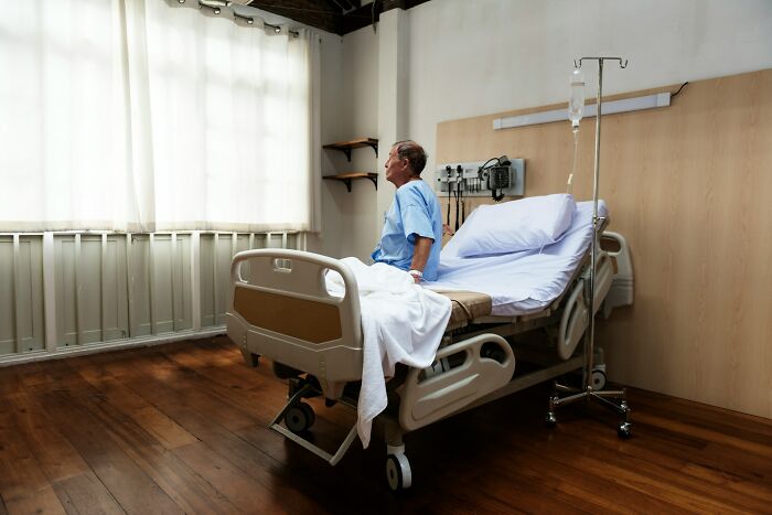 An elderly man sitting on a hospital bed, looking out a window. This image highlights shocking ways people have lost their lives.