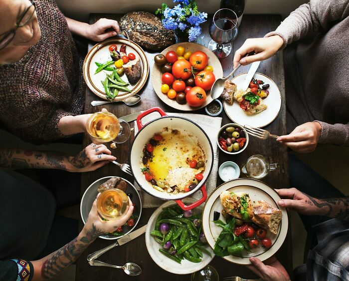 An overhead view of diverse hands reaching for food, illustrating shared culture shocks among international partners.