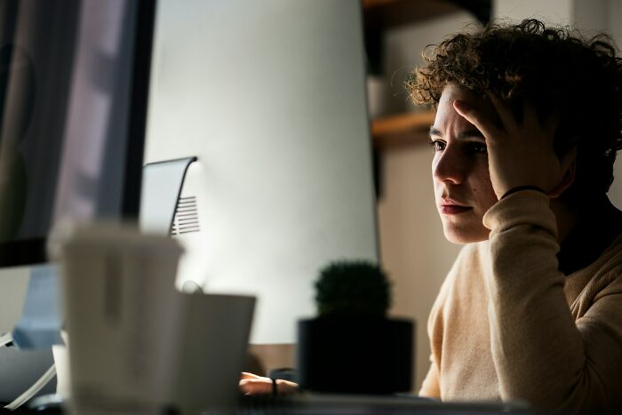 A person looking stressed while working at a computer, possibly due to one of the internet's creepy unsolved mysteries.
