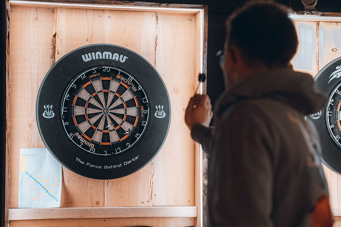 A man holding a dart, aiming at a dartboard, representing examples of infuriating mansplaining.