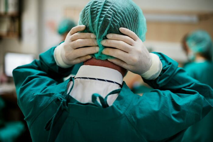 A doctor putting on a surgical cap, representing preparation and the seriousness of avoiding medical mistakes.
