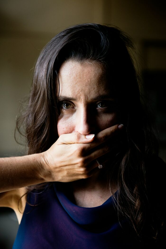 Woman covering her mouth, eyes wide with a sense of deeply evil or unsettling instincts.