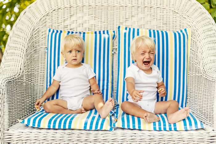 Two babies with blonde hair in white onesies on a striped cushion; one is calm, the other is crying, depicting surprising facts.