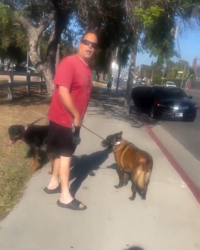 A man with two dogs on a sidewalk, looking toward the camera after being shamed by a Cyclist Karen. A man with two dogs on a sidewalk, looking toward the camera after being shamed by a Cyclist Karen.