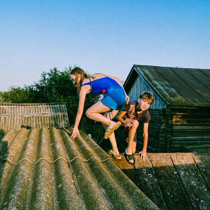 Two children on a rooftop against a blue sky, an adventurous scene potentially from a thrilling babysitting story.