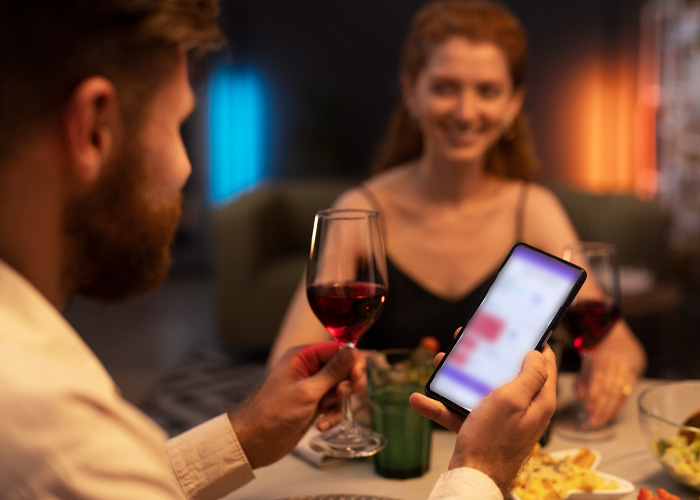 A couple on a date, with one person looking at a dating app on their phone, depicting the new dating method in California colleges. A couple on a date, with one person looking at a dating app on their phone, depicting the new dating method in California colleges.