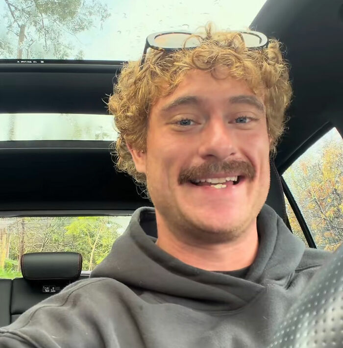 A smiling lonely man in a car, making a crying plea with a visible gap in his teeth. A smiling lonely man in a car, making a crying plea with a visible gap in his teeth.