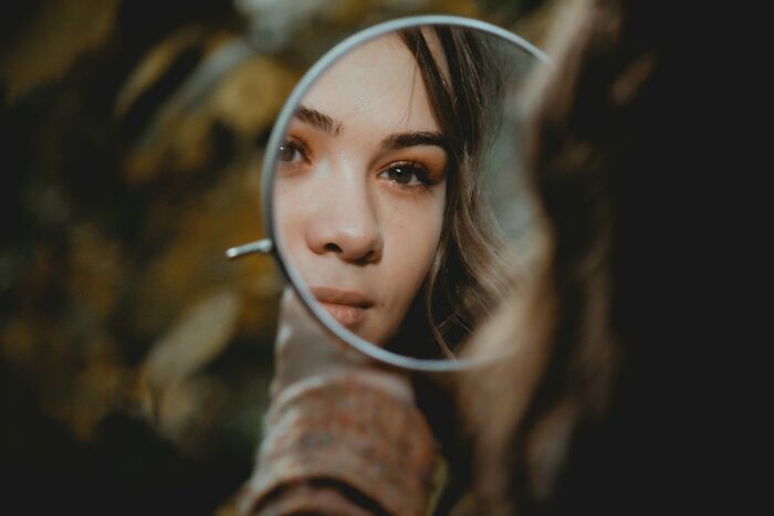 A woman looks into a mirror, reflecting on unhinged therapist moments.