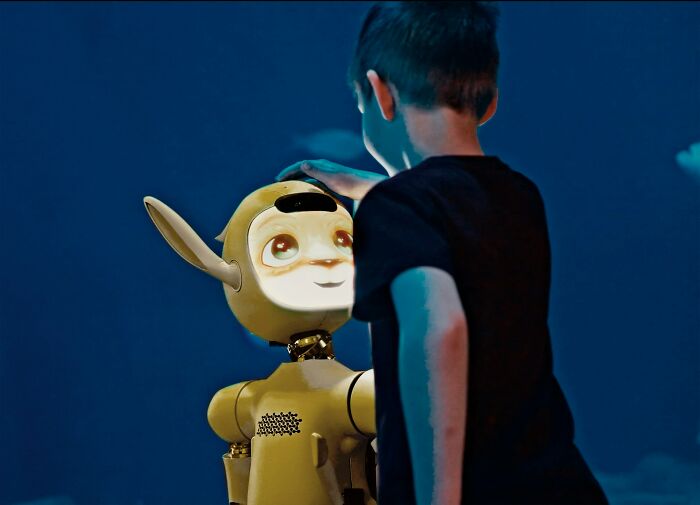 A child gently touching the head of a robot, showcasing an unconventional way to earn money.
