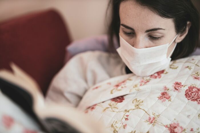 A woman in a face mask reading a book, representing one of the many unsolved mysteries.