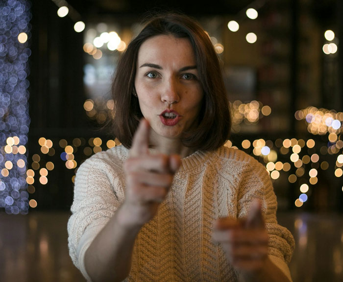 A woman with short brown hair, wearing a cream sweater, points directly at the viewer, representing an entitled aunt. A woman with short brown hair, wearing a cream sweater, points directly at the viewer, representing an entitled aunt.