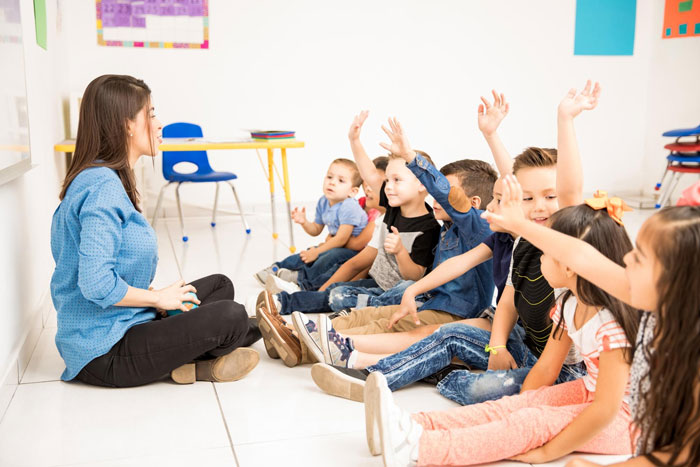 A teacher interacting with children in a community class, some raising hands, highlighting the free daycare aspect. A teacher interacting with children in a community class, some raising hands, highlighting the free daycare aspect.