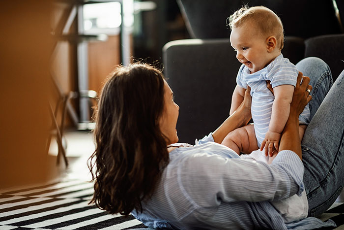 A happy mom playing with her baby, reminding the viewer about the employer-nanny relationship and respecting boundaries.