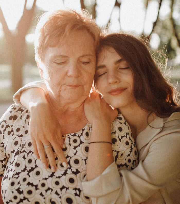 A young woman hugs her great-grandma, illustrating love beyond the grave and family bonds. A young woman hugs her great-grandma, illustrating love beyond the grave and family bonds.