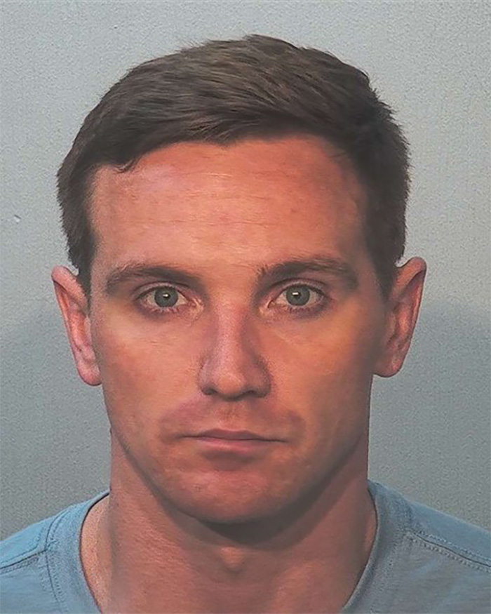 A mugshot of a man with short brown hair and blue eyes, looking directly at the camera, connected to stupid arrests.