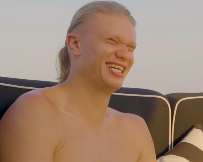 Erling Haaland laughing joyfully, reacting to the internet's funniest memes about him.