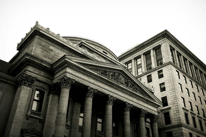 An imposing bank building in black and white, featuring grand columns. This image relates to secrets and how they could do damage.
