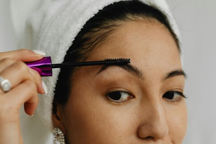 A woman applying mascara to her eyebrows, showing everyday items with completely different uses.