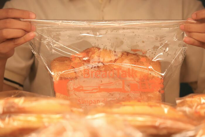 Hands holding a plastic bag of bread, representing everyday items people use for different purposes.