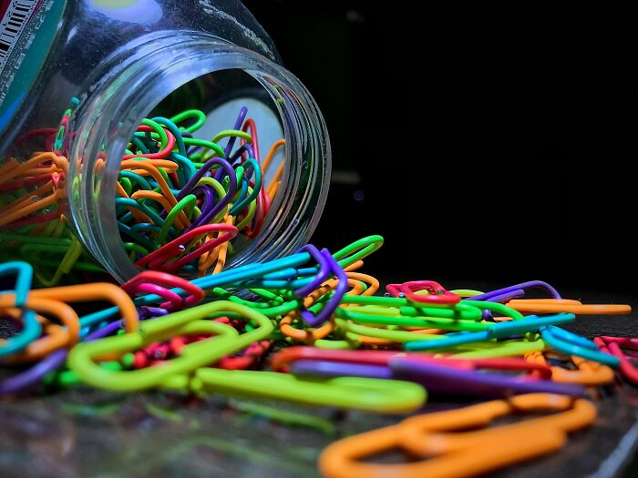 A spilled jar of colorful everyday items, paper clips, used for completely different things.