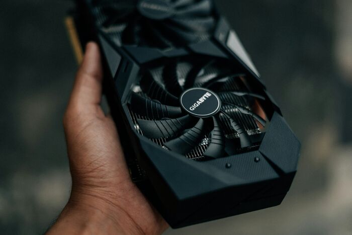 A hand holding an everyday item, a graphics card, which can be used for completely different things.