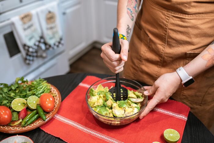 A person using an everyday item, a potato masher, for completely different things, like mashing avocados.