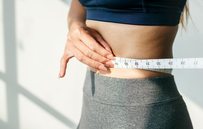 Woman measuring her waist with a tape measure, highlighting everyday items used in different ways.