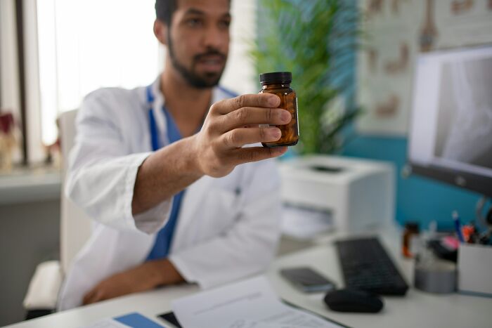 A doctor holding a small brown bottle of pills, highlighting everyday items and their secret uses.