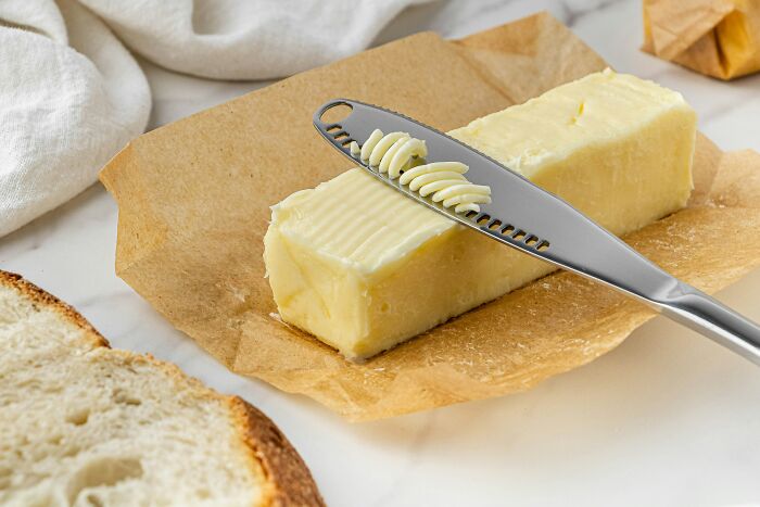 A butter knife curling butter from a stick on parchment paper, showing everyday items used differently.