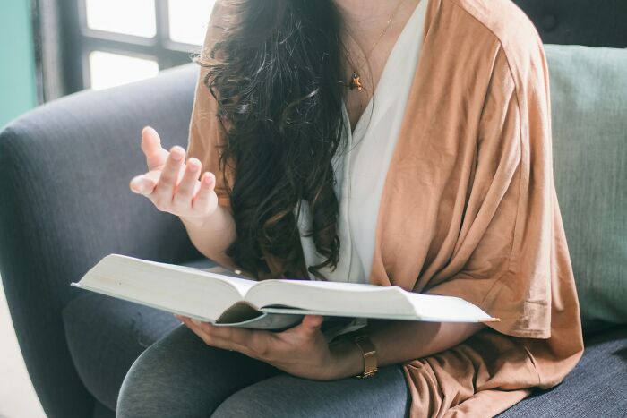 A woman gestures with her hand while holding a book, reflecting on unhinged therapist moments.