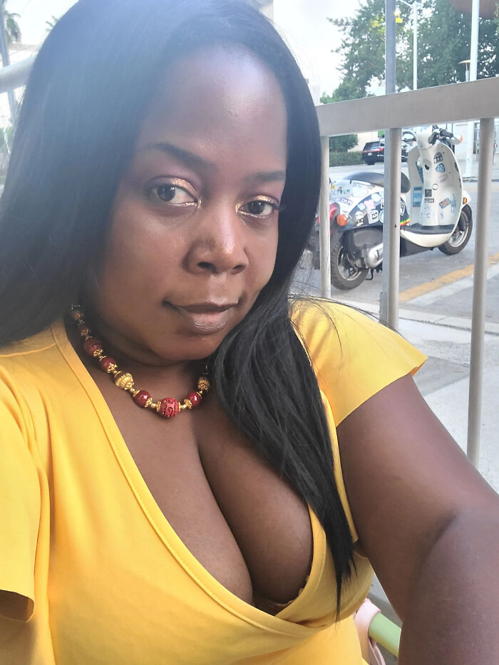 A woman with long dark hair, wearing a yellow shirt and a red and gold necklace, looking at the camera. Her appearance might not match surprising facts about her.
