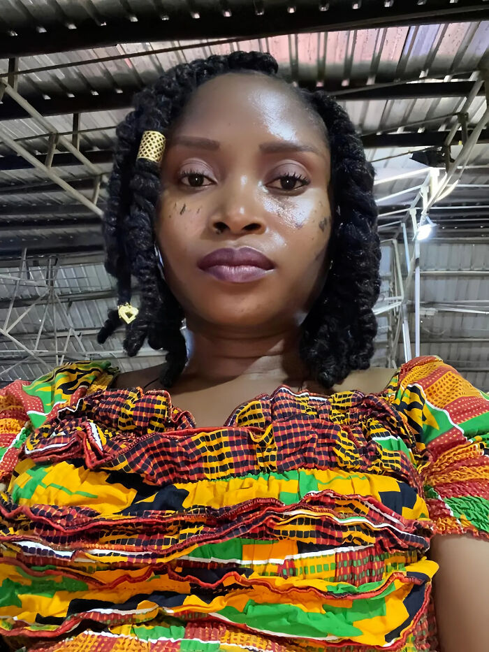 A woman with dark curly hair and a vibrant patterned dress, whose looks don't match surprising facts.