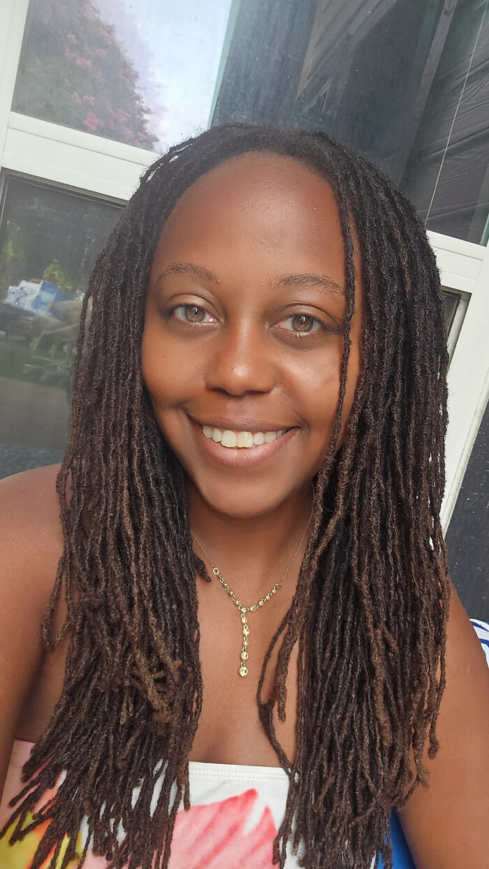 A smiling woman with dreadlocks and a gold necklace, showcasing surprising facts that dont match peoples looks.