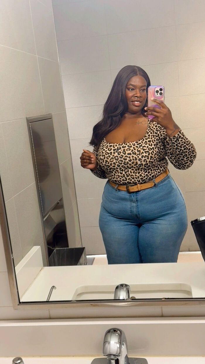 A woman in a leopard print top and jeans taking a mirror selfie, showing surprising facts that dont match peoples looks.