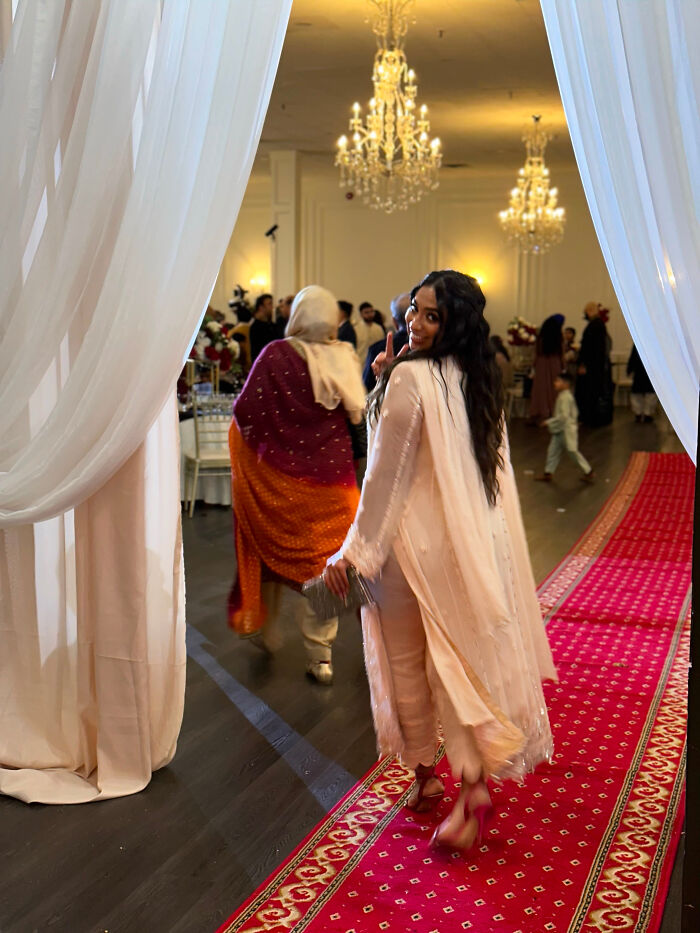 A woman in a light pink outfit walking down a red carpet, turning to look back, showcasing surprising facts.