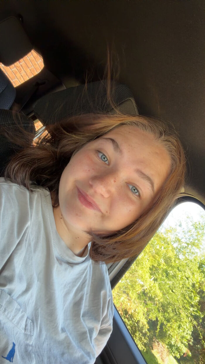 A young woman with blue eyes and freckles smiling in a car, exemplifying surprising facts that don't match people's looks.