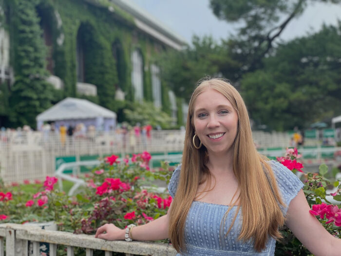 A smiling woman with long blonde hair surrounded by pink roses, showcasing surprising facts that don't match people's looks.