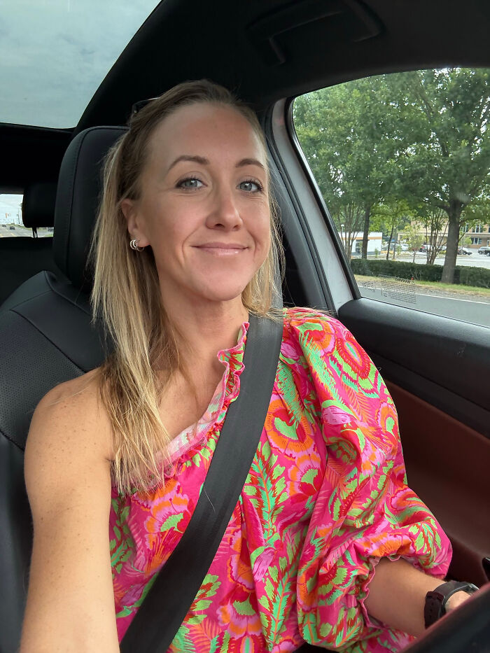 Woman with blonde hair, blue eyes, in a car wearing a colorful pink and green top, sharing surprising facts.