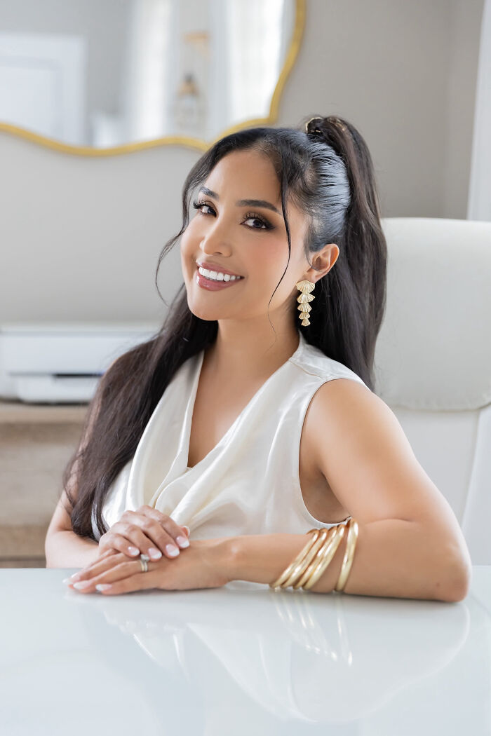Smiling woman with long dark hair, wearing a white satin top and gold bracelets, showcasing surprising facts.