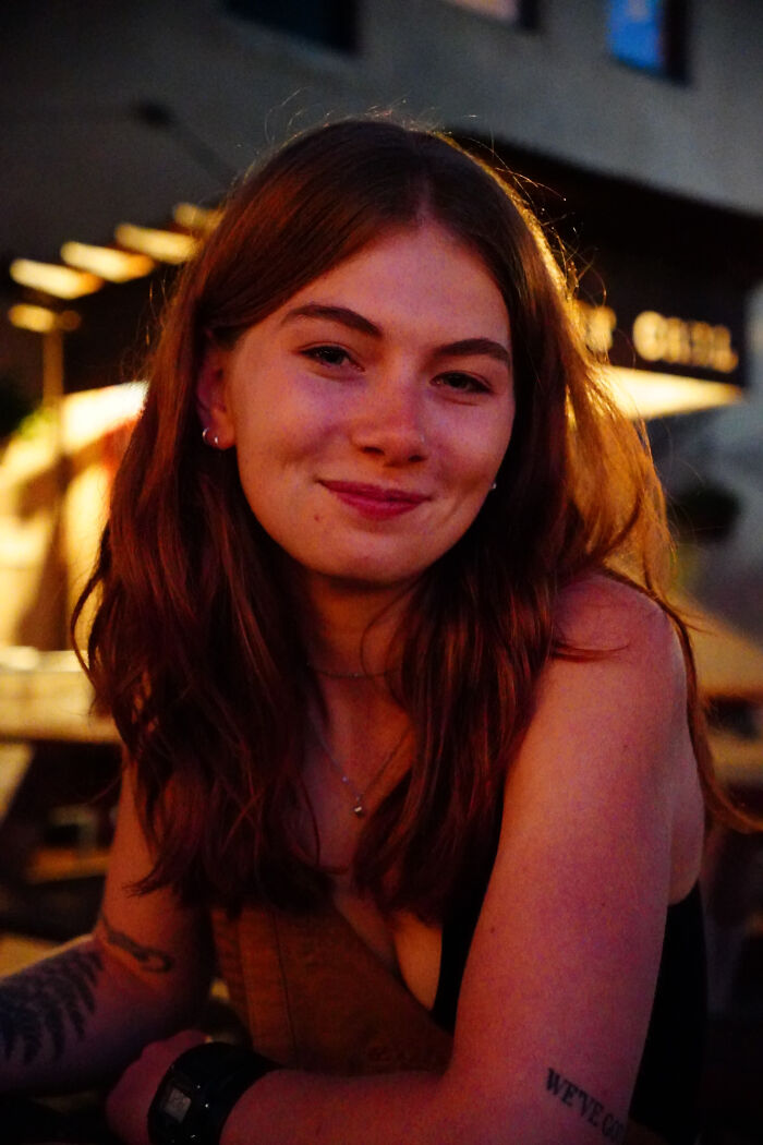 A young woman with long hair smiling at the camera in soft lighting, showcasing surprising facts about people's looks.