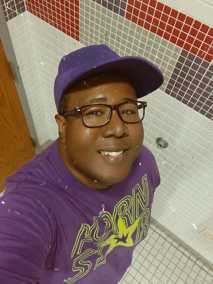 A man wearing a purple cap and glasses, a surprising fact that doesn't match his looks at all, smiling at the camera.
