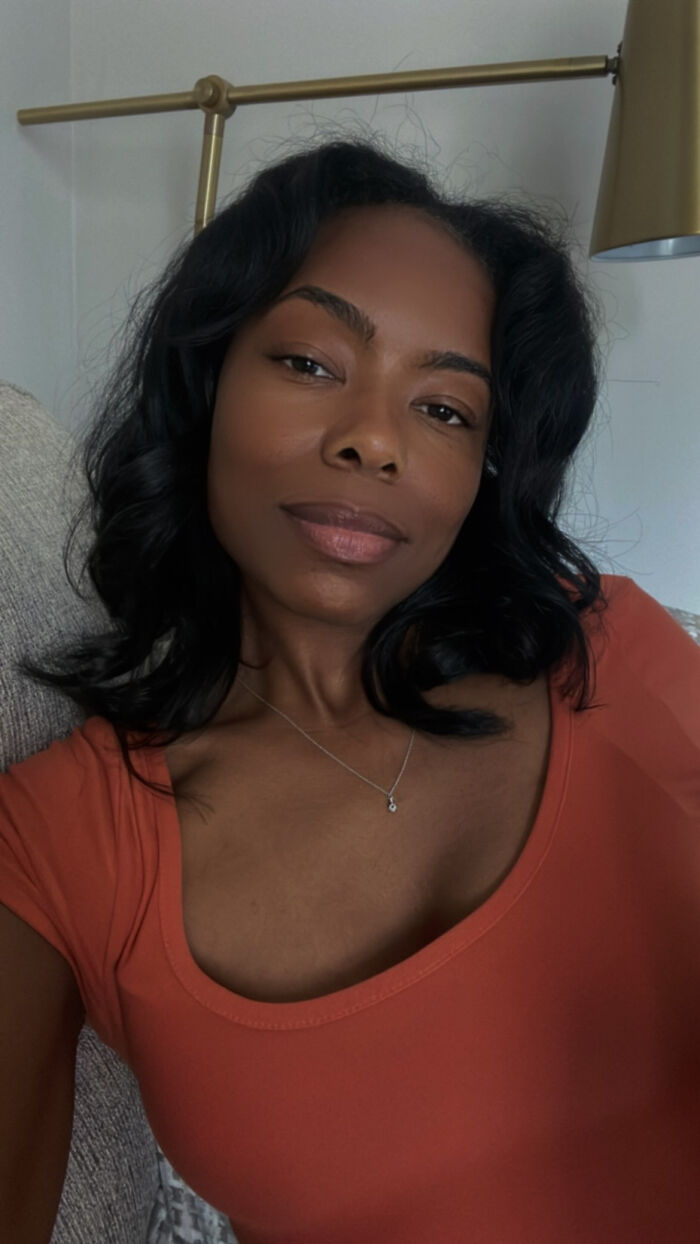A woman with dark hair and an orange top looking directly, presenting surprising facts that dont match her looks.