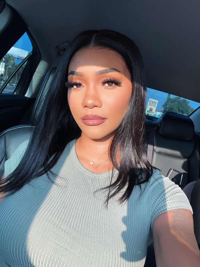 A woman with long dark hair in a car seat, light shining on her, illustrating surprising facts about people's looks.