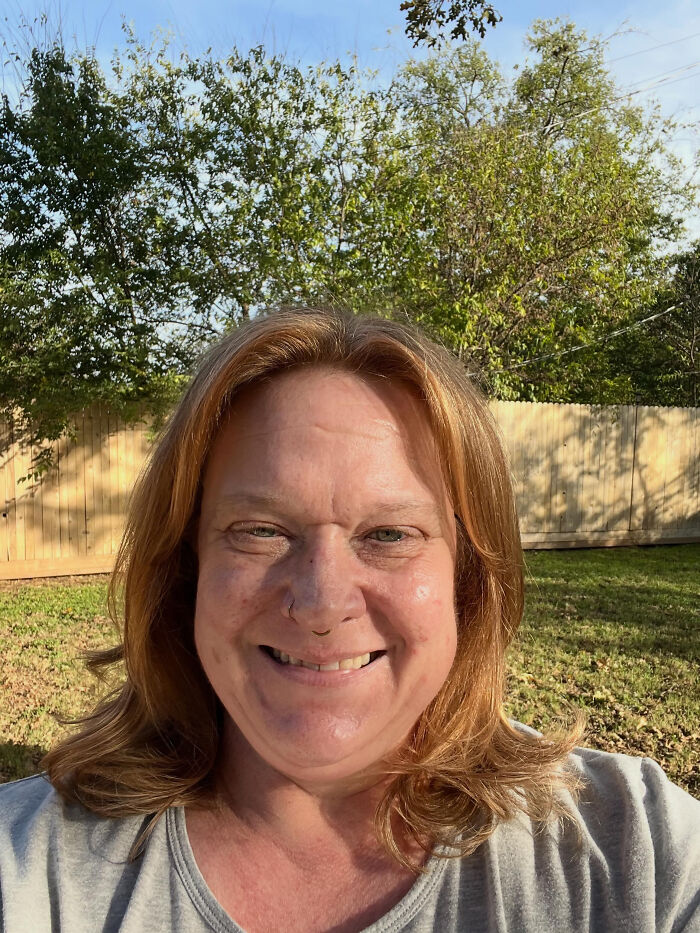 A woman with red hair smiling in a backyard, highlighting surprising facts that don't match people's looks.