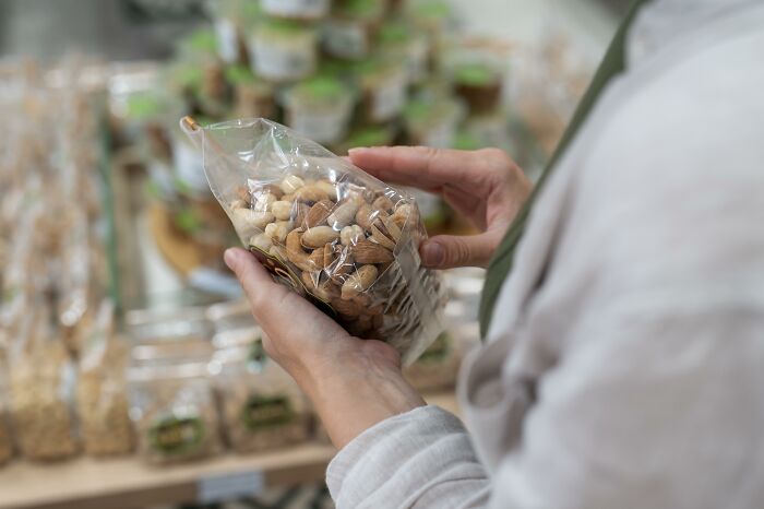 Close-up of hands holding a bag of nuts, representing food packaging, an unpopular industry that makes millions.