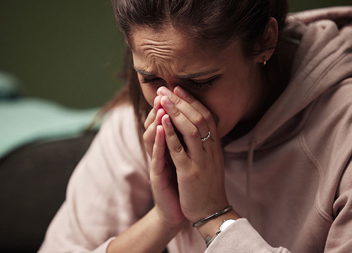 A woman covers her face with her hands, looking distressed after a cruel boyfriend prank. A woman covers her face with her hands, looking distressed after a cruel boyfriend prank.