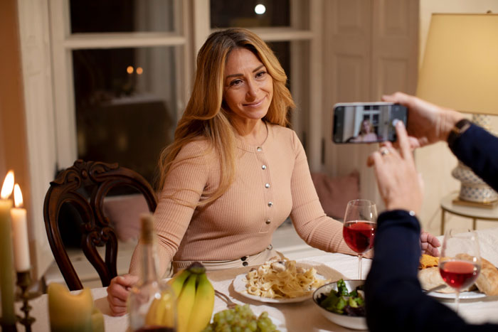A woman at a candlelit dinner, smiling as another person takes her photo, illustrating the gf's secret dating. A woman at a candlelit dinner, smiling as another person takes her photo, illustrating the gf's secret dating.