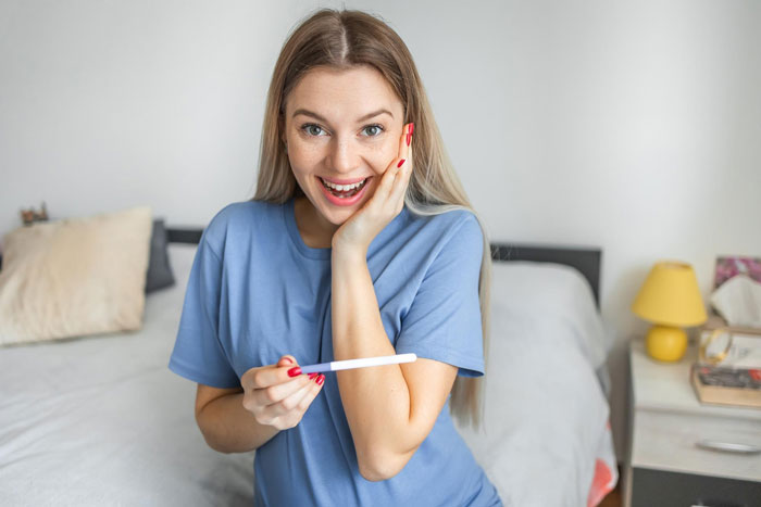 A happy woman holding a pregnancy test, symbolizing the gf's trick related to the bf's secret dating and fake abortion. A happy woman holding a pregnancy test, symbolizing the gf's trick related to the bf's secret dating and fake abortion.